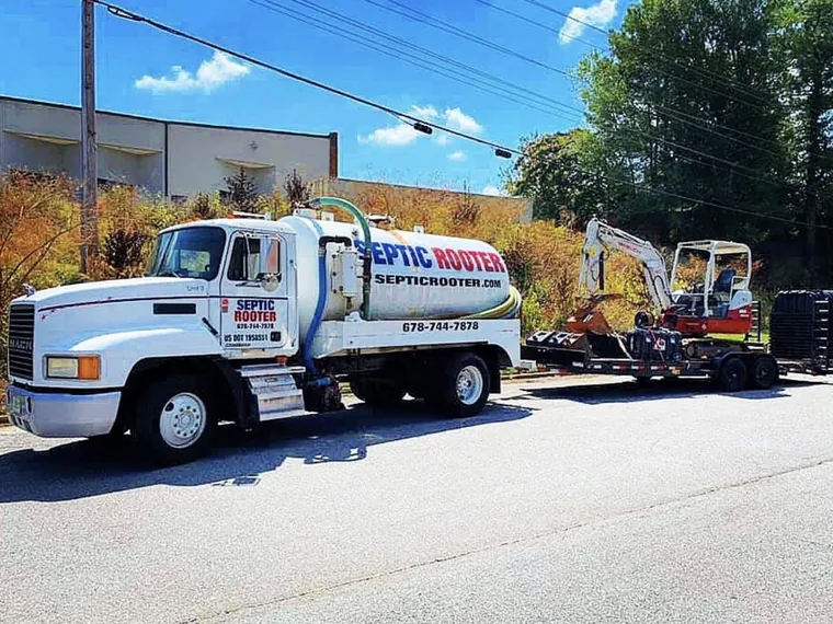 SepticRooter pump truck towing a mini-excavator on a trailer