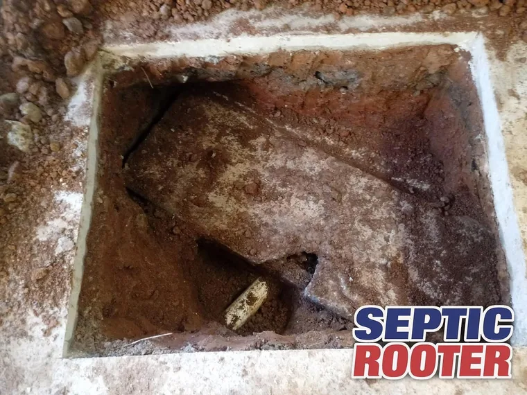 Concrete septic tank exposed in an excavated pit during repair