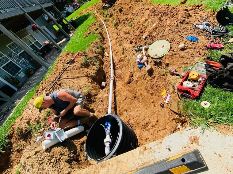 Technician at an opened septic tank with tools during a repair